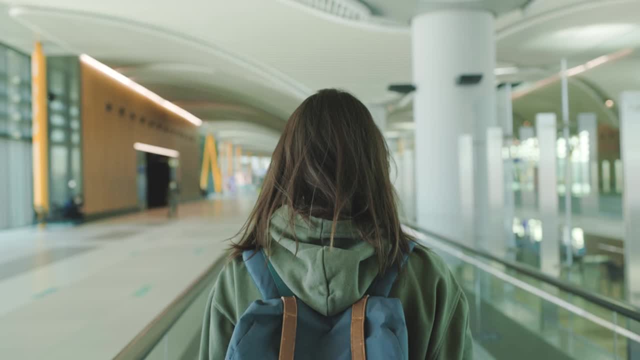 Mujer con mochila en un aeropuerto esperando por un avión.